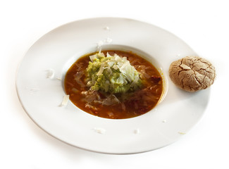 Plate of soup with avocado and cheese garnish and rye bun