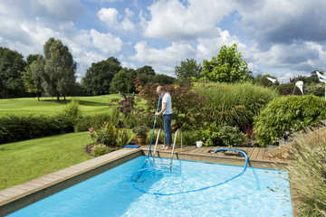 Man Cleaning Swimming Pool - Powered by Adobe
