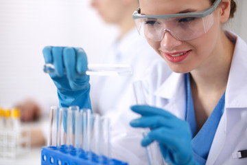 Fototapeta premium Woman researcher is surrounded by medical vials and flasks