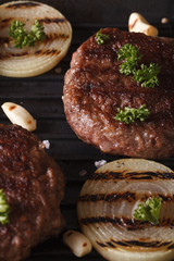 grilled burgers with onions on the grill close up. vertical
