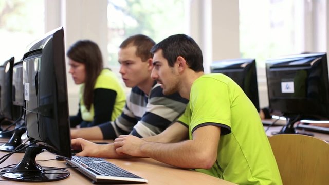 College students sitting in a classroom, using comput