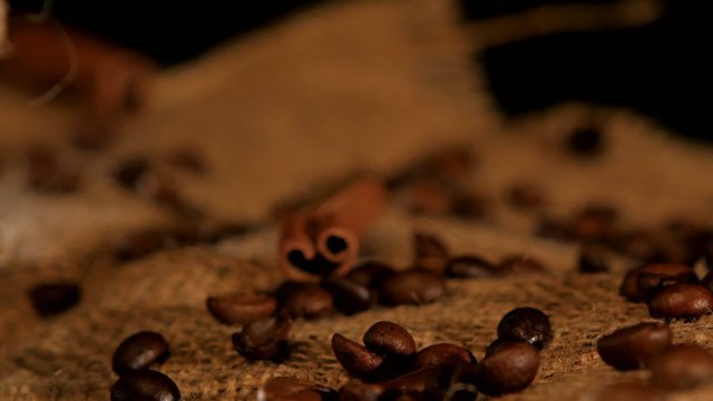 Coffee beans with cinnamon near the coffee bottle on black