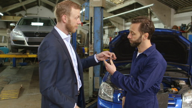 Young businessman handing over a car key to a mechanic