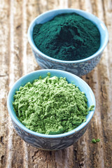 bowl of spirulina algae powder and wheat sprout powder on wooden