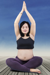 Fototapeta na wymiar Pregnant woman sitting in lotus position