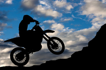 Obraz na płótnie Canvas Motocross - silhouette with a rock and blue sky