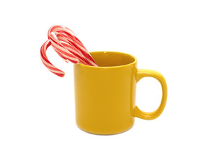 Yellow cup with lollipops sticks isolated on white close up