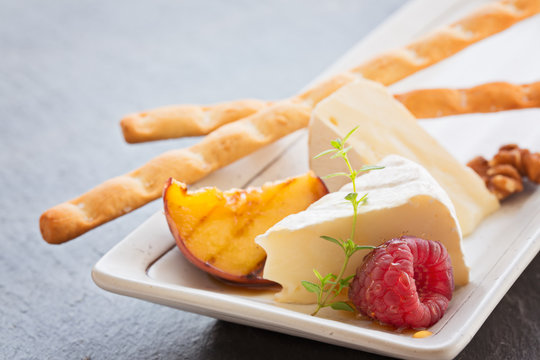 Slice camembert cheese with grilled peach, fresh raspberries and