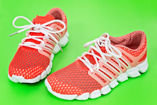 New orange and white running shoes, sneakers or trainers on gree