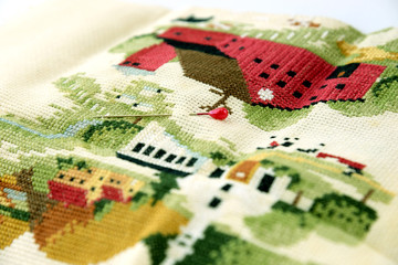 Closeup of needle put into cross-stitch embroidery