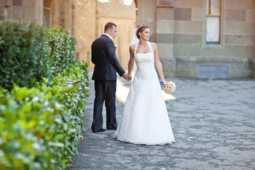 bride and groom are walking in green park