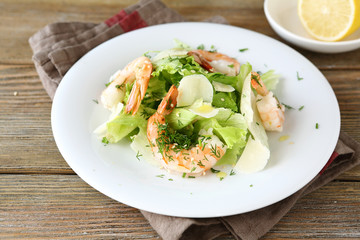 Fototapeta na wymiar Salad with shrimps, lettuce and cheese on a white plate