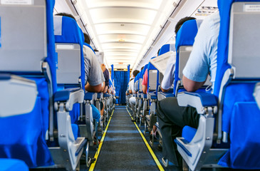 Interior of airplane with passengers on seats - 79428765