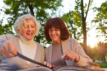 Zwei Seniorinnen lesen Kochbuch im Garten