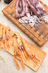 Calamari e scampi crudi su taglieri di legno