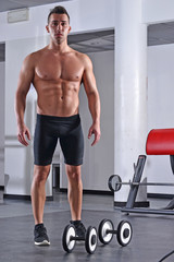 Hombre fuerte deportista entrenando con pesas en gimnasio.