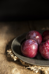 Fresh plums in natural light setting with moody vintage retro st
