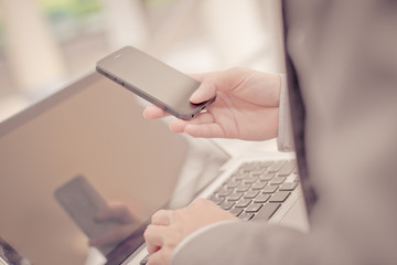Fototapeta premium Businessman using laptop pc and mobile phone. He is sitting on a