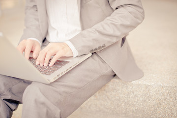 Businessman using laptop pc. He is sitting on a stairs.