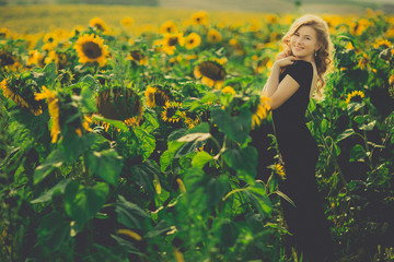 Obraz na płótnie Canvas beautiful girl in black dres, field of sunflowers