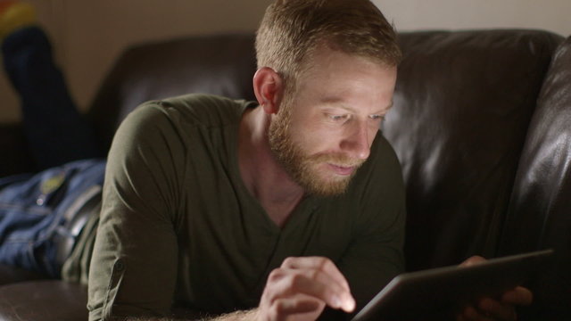 Young man using touchscreen tablet technology and reading.