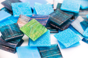 Stack of blue and green glass mosaic tiles on white background © Delphotostock