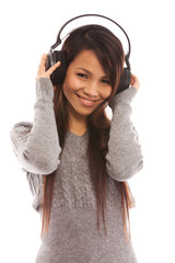 Asian woman is listening music with headphones over white isolat