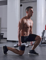 Hombre fuerte deportista entrenando piernas en gimnasio.