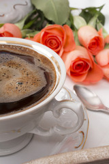 cup of coffee and a bouquet of roses on a tray