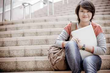 Young woman using laptop on steps outdoors