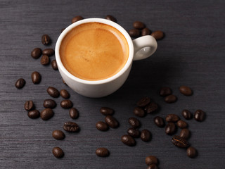 Cup of hot espresso coffee and coffee crop on wood board