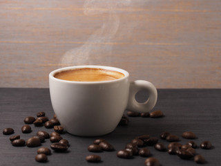 Cup of hot espresso coffee and coffee crop on wood board