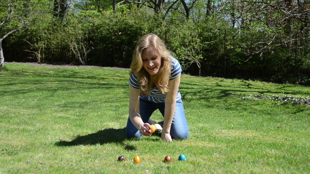 Traditional Easter game. Hand throw roll colorful eggs on grass.