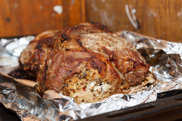 Roasted piece of meat in foil, close-up.