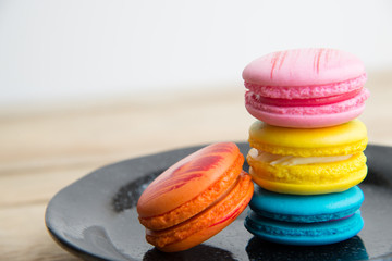 Colorful macaron in black dish on wooden floor