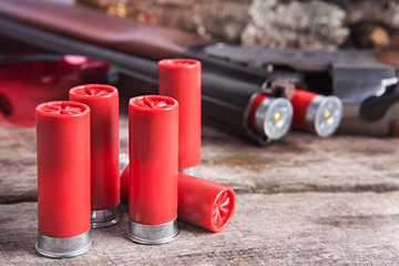 12 gauge shotgun shells with shotgun on wood surface - obrazy, fototapety, plakaty