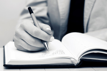 Businesswoman writing in notebook