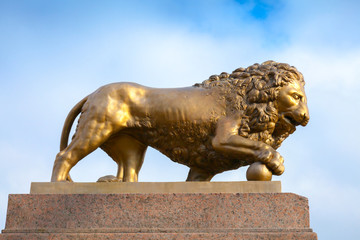 Fototapeta na wymiar Bronze lion with ball, monument on stone base