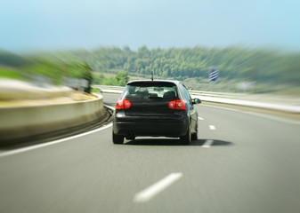 Obraz na płótnie Canvas Black car hurtling down the highway.