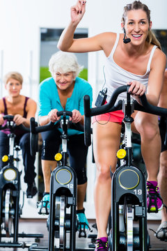 Senioren beim Spinning auf Fitness bike mit Trainer