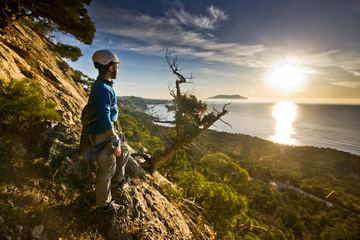 rock climber standing near tree looking on sunrise