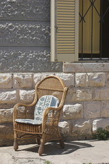 Rattan armchair standin in full sun on a terrace
