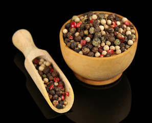 Pepper in wooden bowl, isolated on black