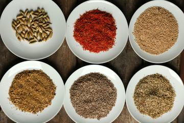 Different spices on plates, on old wooden table