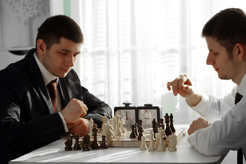 Two handsome businessmen playing chess in office