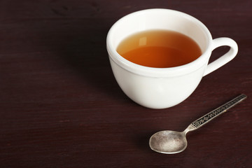 Cup of tea and spoon on color wooden table background