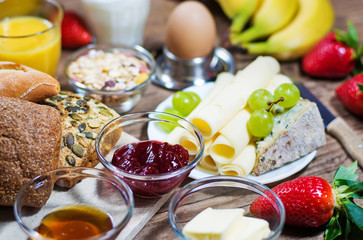 bunter Frühstückstisch mit Brötchen, Obst und Käse