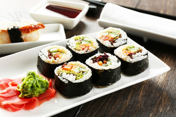 Vegetarian sushi rolls on plate, on wooden background