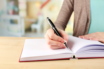 Female hand with pen writing on notebook, closeup