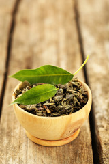 Green tea with leaf in bowl on old wooden table